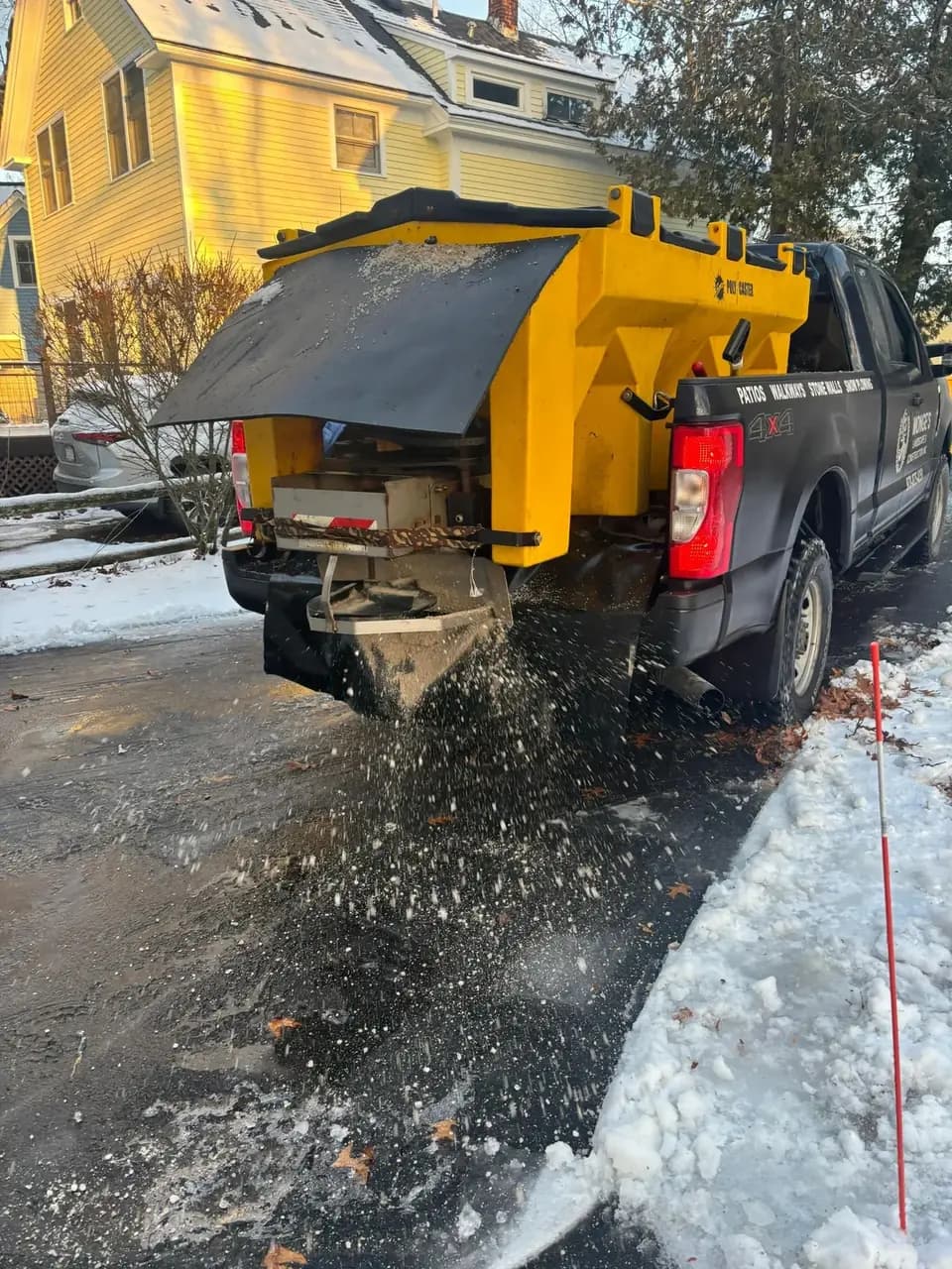 Pickup truck spreading salt on a snowy driveway