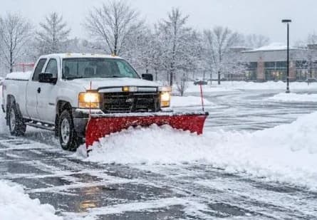 Pickup truck with a snowplow in a snow-covered parking lot